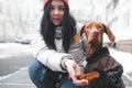 Portrait of a smiling girl and a dog in warm clothes sitting in the winter on the street, the dog gives her foot a woman. Girl and