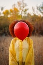 Woman in a yellow raincoat holding a red balloon on the background of forest. Royalty Free Stock Photo