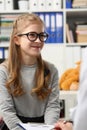 Portrait of smiling girl in glasses at doctor appointment.