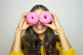 Portrait of smiling girl having fun with sweets isolated on gray background. Attractive young woman with long hair posing with dou Royalty Free Stock Photo