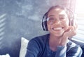 Portrait of smiling girl with headphones listening to music while sitting on sofa at home Royalty Free Stock Photo