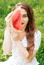 Portrait of a smiling girl holds watermelon slice covers half part of her face.