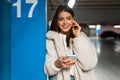 Portrait of smiling girl with phone in hands who correcting the earphone in her ear. Young fashionable woman with phone Royalty Free Stock Photo