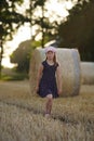 Portrait of smiling girl playing, jumping and running on grass hay field paths of dry grass in the sunset. Waving hands Royalty Free Stock Photo