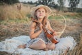 Portrait of smiling girl sitting on blanket in dry hay field, having picnic, learning playing guitar ukulele Royalty Free Stock Photo