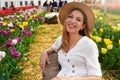 Portrait of smiling girl sitting relaxed between tulips fields on springtime. Looking at camera