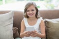 Portrait of smiling girl sitting on sofa using mobile phone in living room Royalty Free Stock Photo