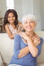 Portrait of smiling granddaughter embracing her grandmother in living room Royalty Free Stock Photo