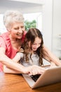 Portrait of smiling grandmother and granddaughter using laptop Royalty Free Stock Photo