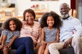 Portrait Of Smiling Grandparents With Grandchildren Sitting On Sofa At Home Relaxing Together