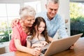 Portrait of smiling grandparents and granddaughter using laptop Royalty Free Stock Photo