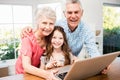 Portrait of smiling grandparents and granddaughter using laptop Royalty Free Stock Photo