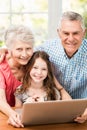 Portrait of smiling grandparents and granddaughter using laptop Royalty Free Stock Photo