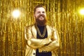 Portrait of happy man in shiny golden disco jacket standing arms folded and smiling