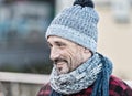 Aged man in winter hat and scarf. Portrait of smiling guy on street. Guy in knitted hat with ball