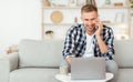 Portrait of smiling guy using pc talking on smartphone Royalty Free Stock Photo