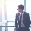 Portrait of a smiling handsome businessman on a window background looking to the side of a virtual text Royalty Free Stock Photo