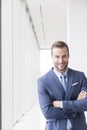 Portrait of smiling handsome young businessman standing with arms crossed in new office Royalty Free Stock Photo