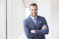 Portrait of smiling handsome young businessman standing with arms crossed in new office Royalty Free Stock Photo