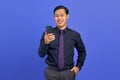 Portrait of smiling handsome young businessman using smartphone on purple background Royalty Free Stock Photo