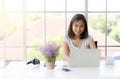 Portrait of smiling happy beautiful asian woman using laptop and typing on keyboard at home Royalty Free Stock Photo