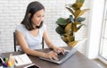 Portrait of smiling happy beautiful asian woman using technology of laptop computer while sitting on table and typing on keyboard Royalty Free Stock Photo