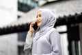Portrait of smiling happy beautiful muslim woman relaxing using digital smartphone in the city Royalty Free Stock Photo