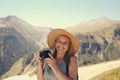 Portrait of a smiling happy elderly woman tourist traveling with a camera posing against backdrop of mountains. Old Royalty Free Stock Photo
