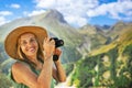 Portrait of a smiling happy elderly woman tourist traveling with a camera posing against backdrop of mountains. Old Royalty Free Stock Photo