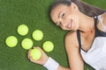 Portrait of Smiling and Happy Female Sportswoman Lying on Artificial Grass Surface With Tennis Balls