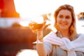 Portrait of smiling happy woman with long wavy fair hair, wearing white sweater, grey shirt, standing on embankment. Royalty Free Stock Photo