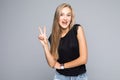 Portrait of a smiling happy woman showing victory sign and looking at camera isolated on the gray background Royalty Free Stock Photo