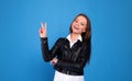 Portrait of a smiling happy woman showing victory sign and looking at camera isolated on the gray background Royalty Free Stock Photo