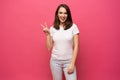 Portrait of a smiling happy woman showing victory sign and looking at camera isolated on the pink background. Royalty Free Stock Photo