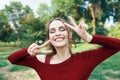 Portrait of a smiling happy woman showing victory sign posing outdoors on green summer nature background. Royalty Free Stock Photo