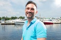 Portrait of smiling happy yachtsman on marina with boat background. Summer vacation yachting time for male lifestyle