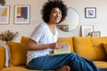 Portrait of smiling, happy young African American woman reading a book at home looking at camera. Royalty Free Stock Photo