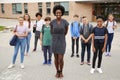 Portrait Of Smiling High School Student Group With Female Teacher Standing Outside School Buildings