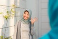 Portrait of A smiling hijab woman welcomed her friend in front of her house door