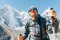 Portrait of smiling Hiker man on Taboche 6495m and Cholatse 6440m peaks background with trekking poles, UV protecting sunglasses.