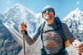 Portrait of smiling Hiker man on Taboche 6495m and Cholatse 6440m peaks background with trekking poles, UV protecting sunglasses.