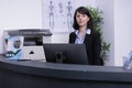 Portrait of smiling hospital receptionist standing at front desk waiting for appointments Royalty Free Stock Photo