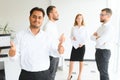 Portrait of smiling indian businessman standing in modern office on colleagues background Royalty Free Stock Photo