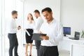 Portrait of smiling indian businessman standing in modern office on colleagues background Royalty Free Stock Photo