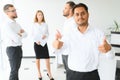 Portrait of smiling indian businessman standing in modern office on colleagues background Royalty Free Stock Photo