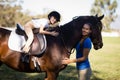 Portrait of smiling jockey and girl embracing horse Royalty Free Stock Photo