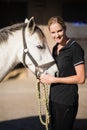 Portrait of smiling jockey stroking horse at barn Royalty Free Stock Photo