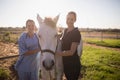 Portrait of smiling jockey and vet standing by horse at barn