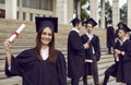 Portrait of smiling joyful girl student in a university graduate gown and diploma in her hands. Royalty Free Stock Photo