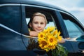 Portrait of smiling kid boy teen look from the car holding bouquet of flowers. Holiday, travel and adventure concept